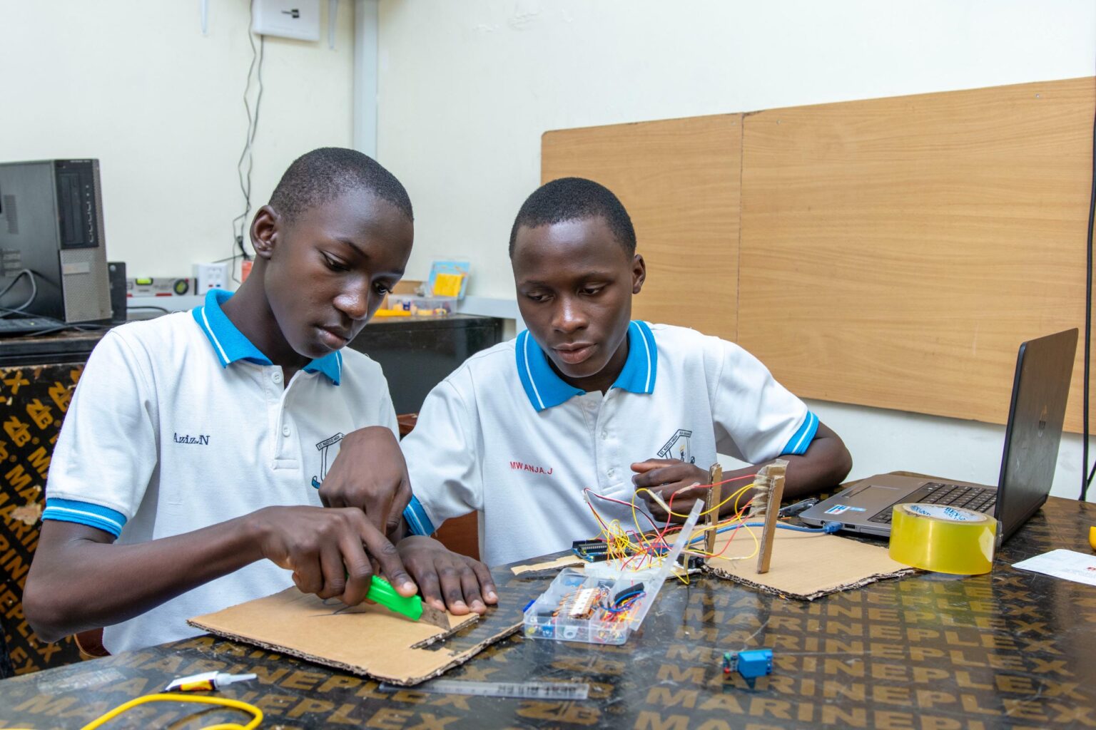 Students at St Kizito High School building an electronics project with a laptop